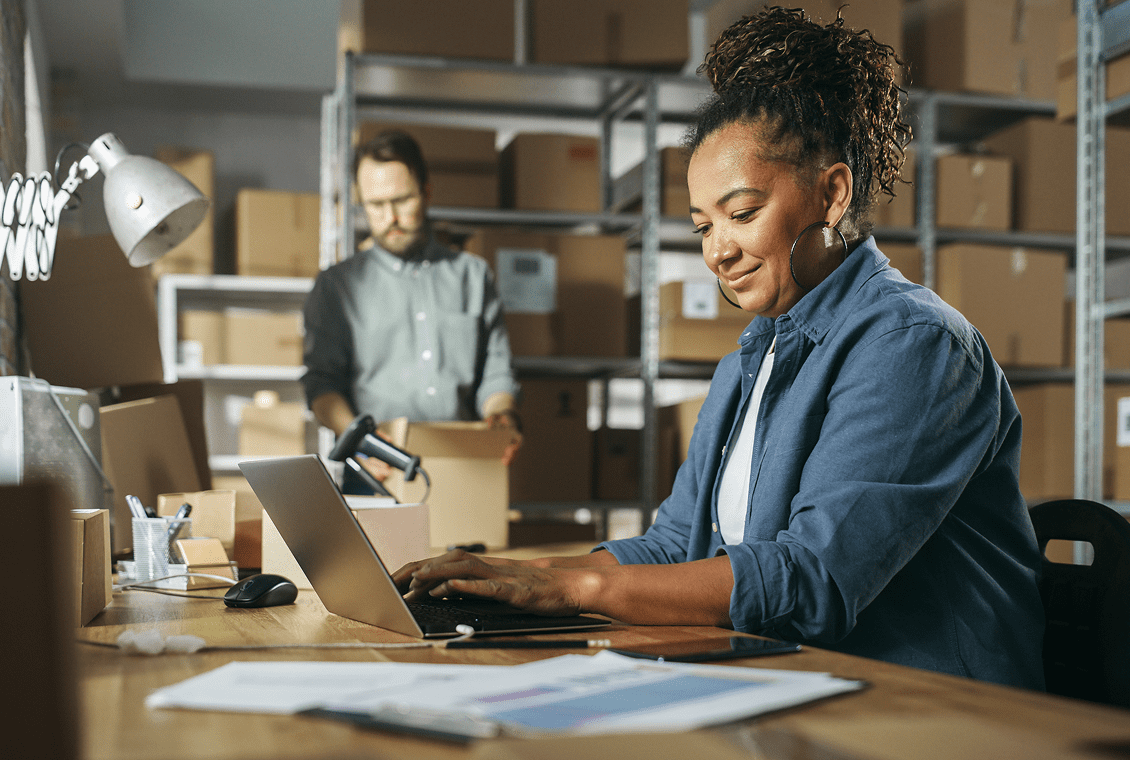 Woman working on laptop in warehouse